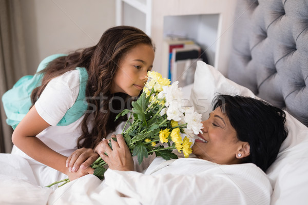 Stock photo: Girl giving bouquet to sick grandmother at home