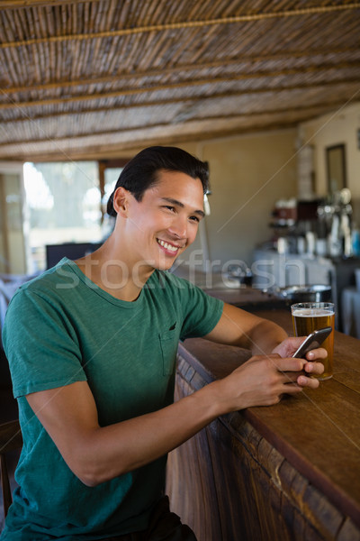 Smiling man looking away while using phone at bar Stock photo © wavebreak_media