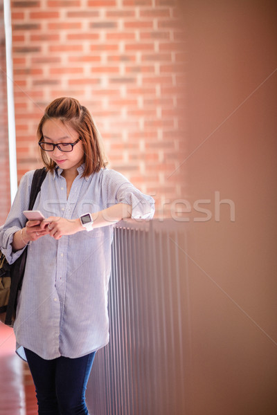 Stock photo: Young woman using mobile phone in corridor