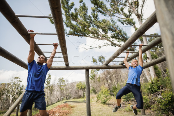 Fit man and woman climbing monkey bars during obstacle course Stock photo © wavebreak_media