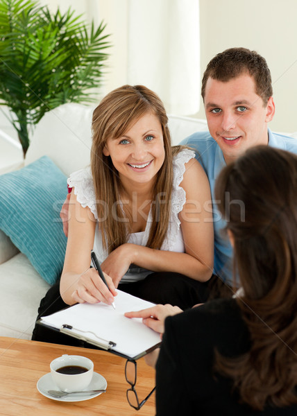 Loving young couple signing a contract sitting in the living room with a saleswoman Stock photo © wavebreak_media