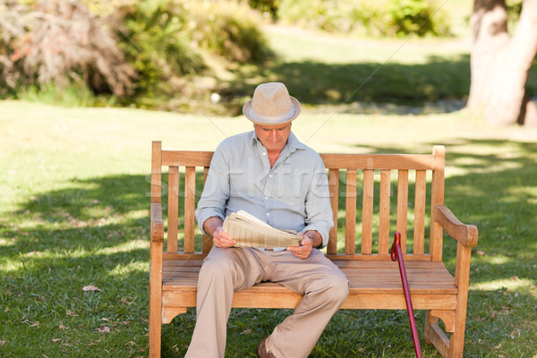 Stock photo: Retired man reading his newspaper on the bench