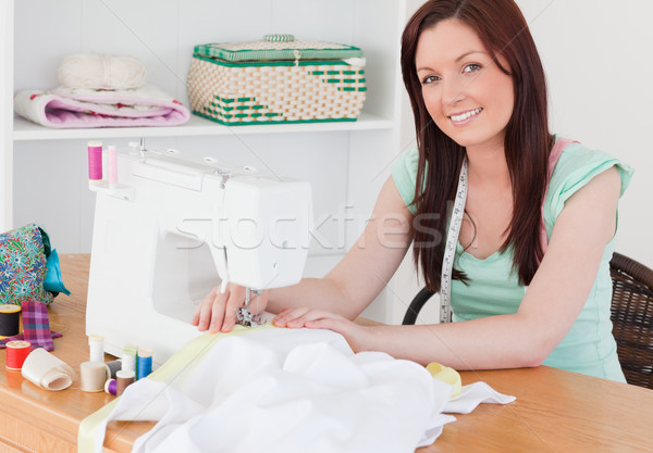 Attractive red-haired female using a sewing machine in her living room Stock photo © wavebreak_media