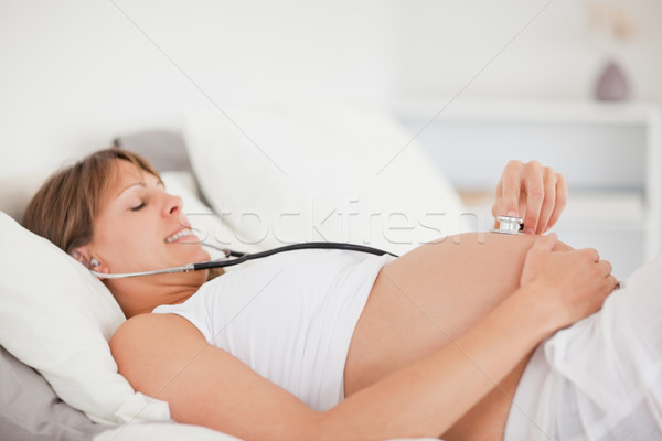 Cute беременная женщина стетоскоп кровать квартиру женщину Сток-фото © wavebreak_media