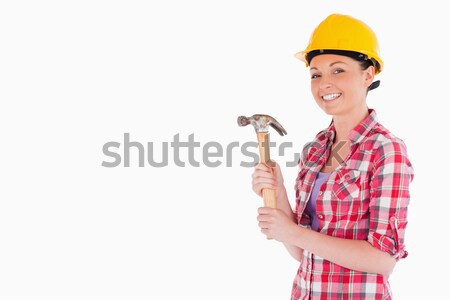 Stock photo: Attractive woman holding a hammer while standing against a white background