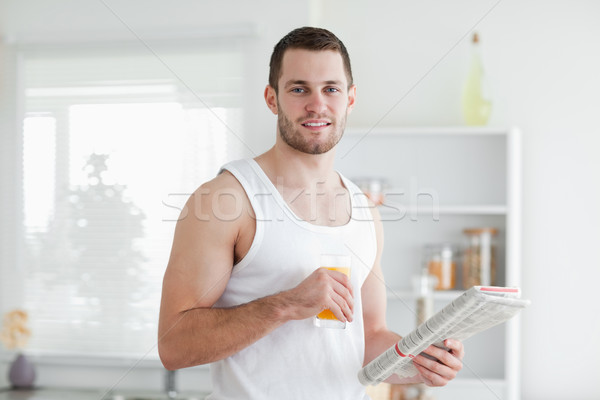 Smiling man drinking orange juice while reading the news in his kitchen Stock photo © wavebreak_media