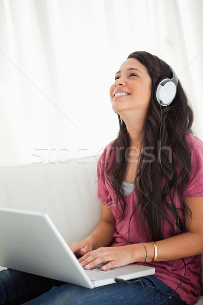 Close-up of a laughing Latino student using a laptop while enjoying music on her sofa Stock photo © wavebreak_media