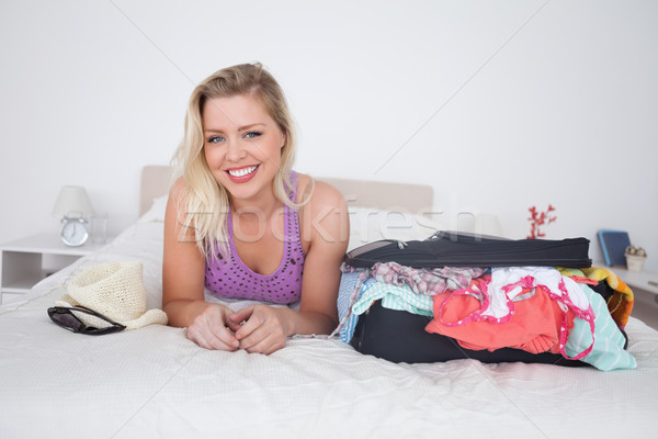 Blonde lying on her bed next to a full suitcase in her bedroom Stock photo © wavebreak_media