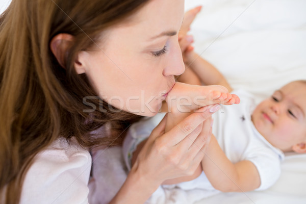 Mother kissing her babys leg on bed Stock photo © wavebreak_media