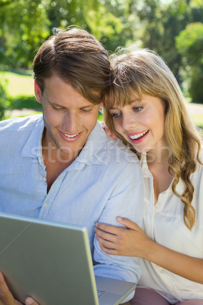 Cute couple sitting on park bench together looking at laptop Stock photo © wavebreak_media