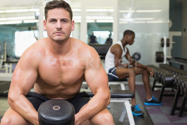 Handsome bodybuilder holding heavy black dumbbell Stock photo © wavebreak_media