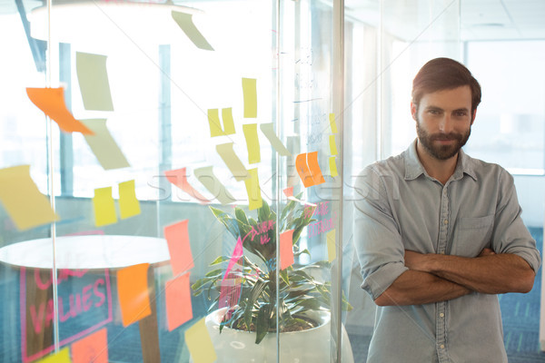 Portrait of confident businessman with arms crossed standing by strategy on glass at office Stock photo © wavebreak_media