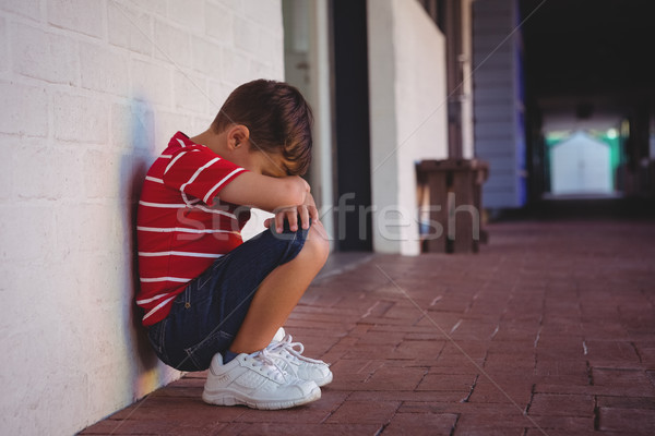 Side view of depressed boy crouching by wall Stock photo © wavebreak_media