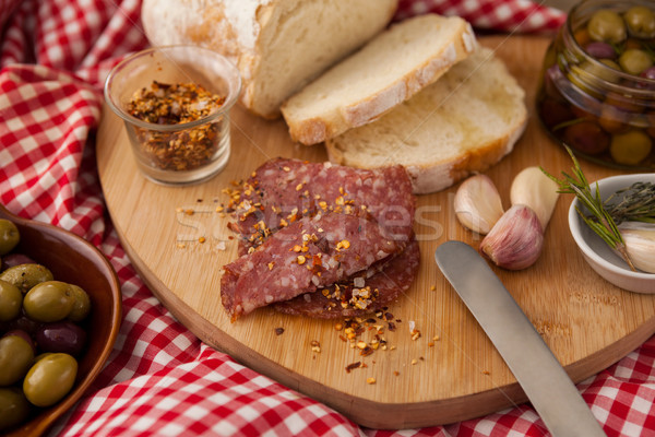 Chili flakes on meat by bread with olives in jar Stock photo © wavebreak_media