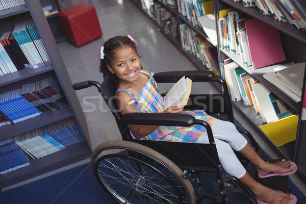 Portrait of smiling girl with book on wheelchair Stock photo © wavebreak_media