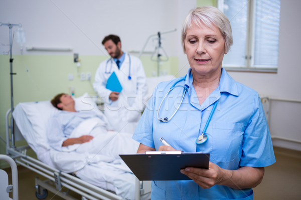 Stock photo: Nurse writing on clipboard