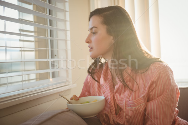 Stock photo: Woman looking through window while sitting on sofa