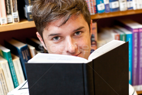 Portrait of a good-looking male student reading a book sitting on the floor Stock photo © wavebreak_media