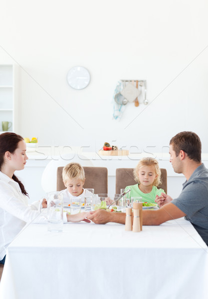 Stock photo: Family holding their hands while praying before eating a salad in the kitchen