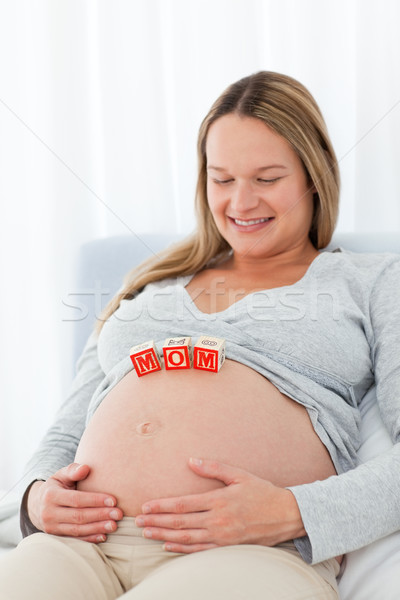 Cute pregnant wife looking at mom letters on her belly while relaxing on a bed Stock photo © wavebreak_media