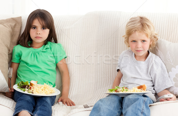 Serious brother and sister having dinner on the sofa Stock photo © wavebreak_media