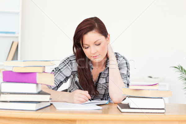 Beautiful happy red-haired girl studying for an examination at her desk Stock photo © wavebreak_media