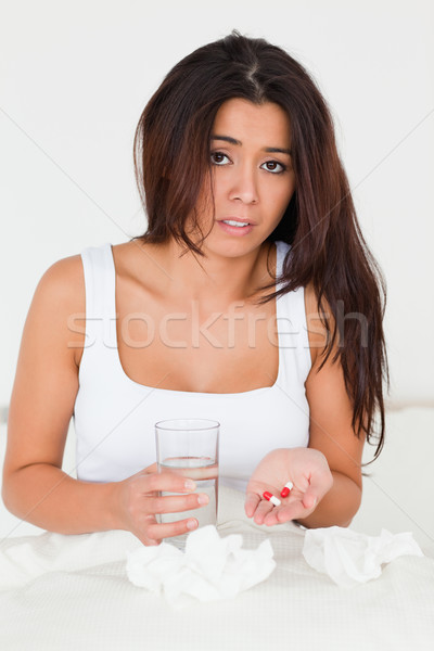 dark-haired woman having a cold sitting in bed taking pills looking into camera in bedroom Stock photo © wavebreak_media