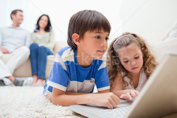 Boldog gyerekek laptopot használ szőnyeg szülők mögött Stock fotó © wavebreak_media