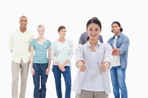 People behind a woman smiling with her the thumbs-up against white background Stock photo © wavebreak_media