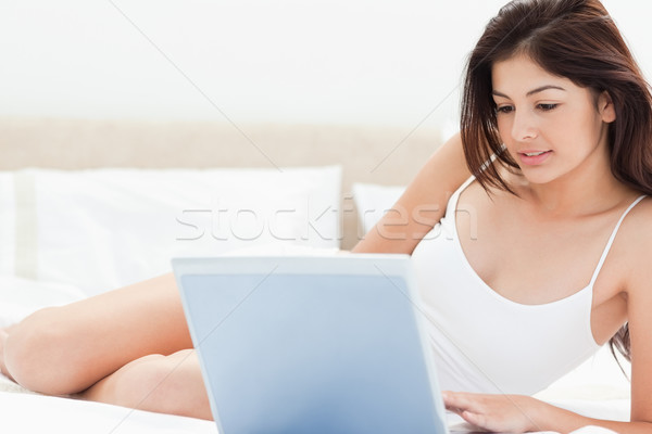A woman using her laptop in front of her to browse while she lies on her bed. Stock photo © wavebreak_media