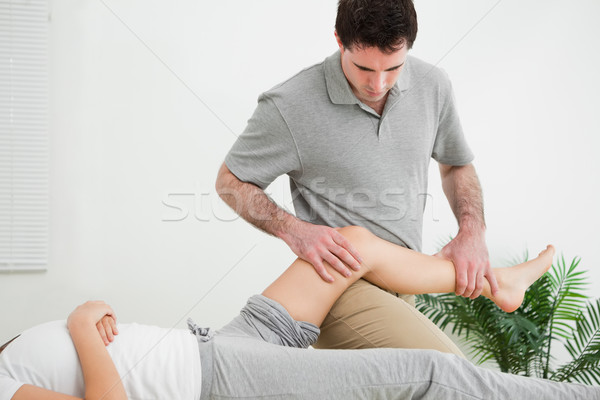 Masseur massaging the leg of a woman while placing it on his thigh in a room Stock photo © wavebreak_media