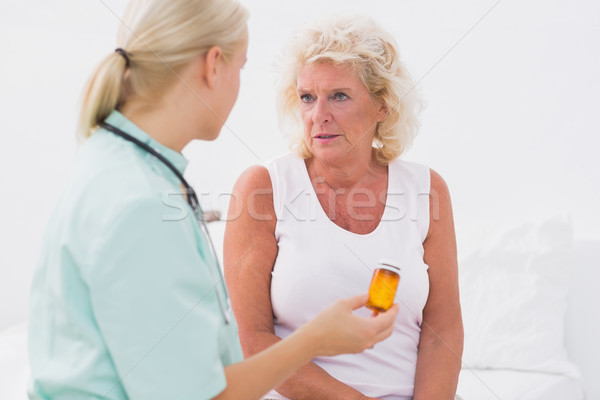 Home nurse showing a pill bottle to her patient Stock photo © wavebreak_media