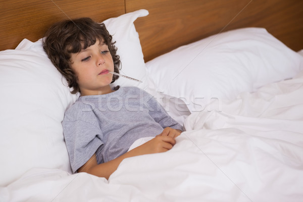 Sick child with thermometer resting in bed Stock photo © wavebreak_media