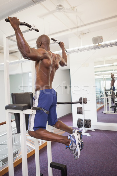Stock photo: Male body builder doing pull ups at the gym
