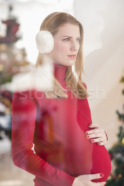 Pretty pregnant woman caressing her belly while standing Stock photo © wavebreak_media