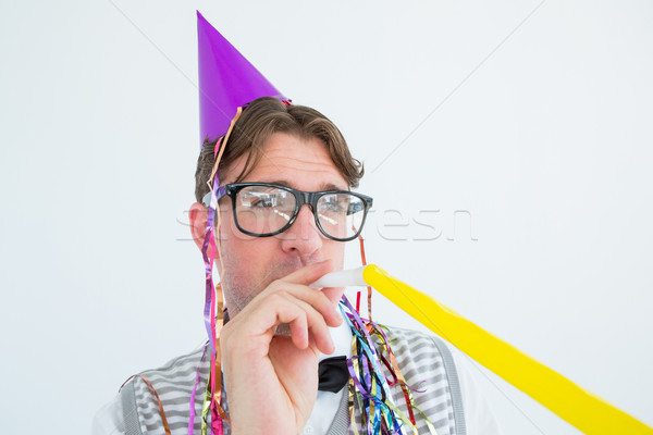 Geeky hipster wearing a party hat with blowing party horn Stock photo © wavebreak_media