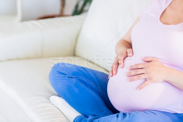 Close up of pregnant woman sitting on couch touching her belly Stock photo © wavebreak_media