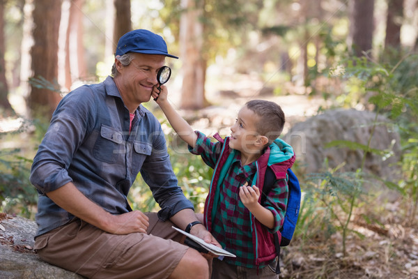 Boy showing magnifying glass to father while hiking in forest Stock photo © wavebreak_media