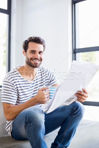Portrait of happy man on steps holding cup of coffee and reading Stock photo © wavebreak_media