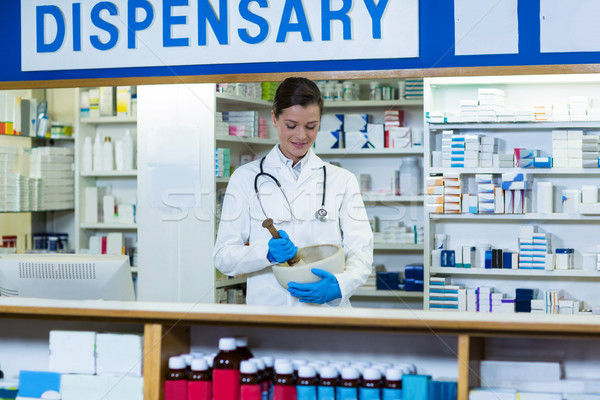 Stock photo: Pharmacist grinding medicine in mortal and pestle at counter