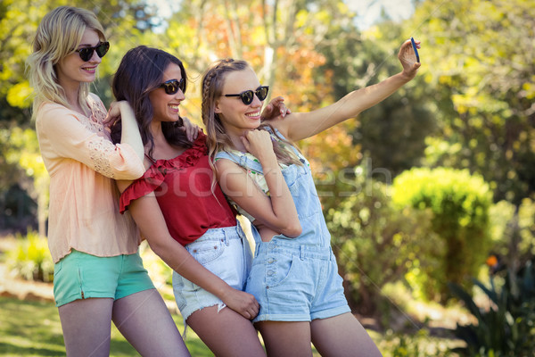 Amigos toma teléfono móvil sonriendo parque Foto stock © wavebreak_media