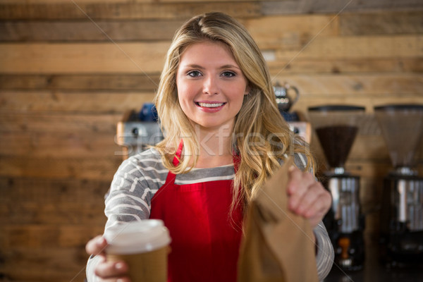 Smiling female barista holding coffee cup and paper bag in cafeteria Stock photo © wavebreak_media