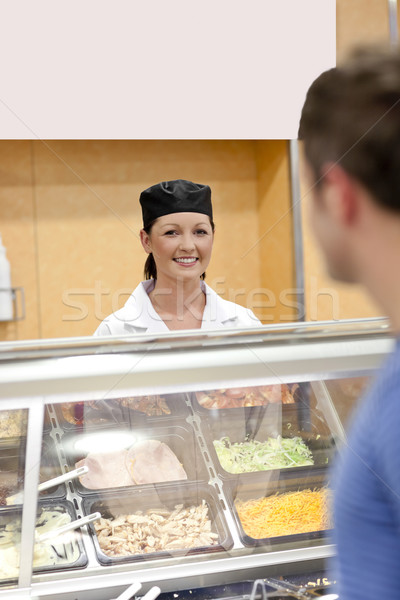 Beautiful cook standing behind the refrigerated display in a cafeteria waiting for a customer in the Stock photo © wavebreak_media