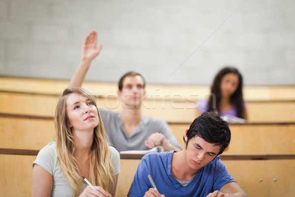 Students taking notes while their classmate is raising his hand in an amphitheater Stock photo © wavebreak_media