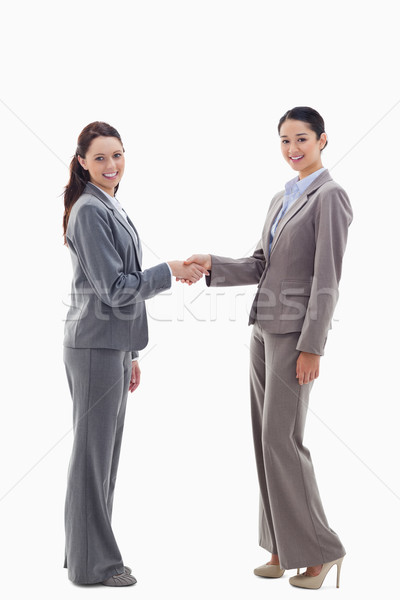 Two businesswomen shaking hands and smiling against white background Stock photo © wavebreak_media