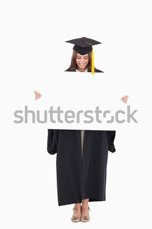 A woman holding a blank sheet in front of her and she looks down at it while smiling Stock photo © wavebreak_media