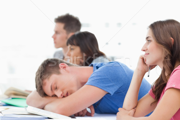 Stock photo: A group of listening students in class as another student has fallen asleep 