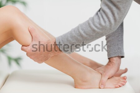 Stock photo: Doctor using his fingertips to massage a thigh in a room
