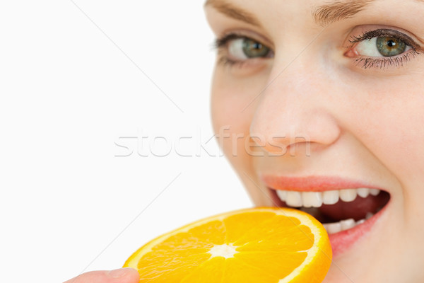 Close up of a woman placing a slice of an orange in her mouth against white background Stock photo © wavebreak_media