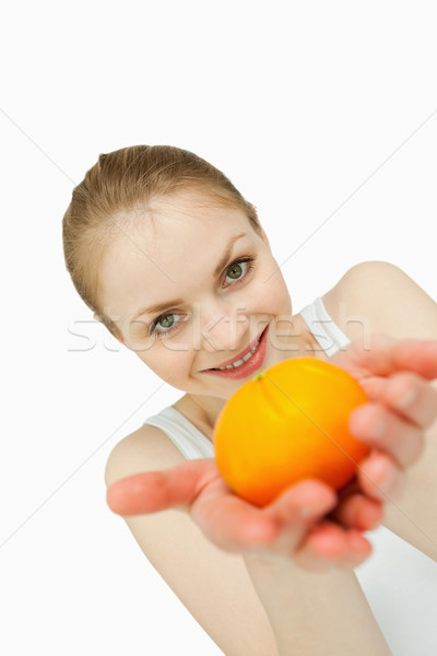 Young woman presenting a tangerine against white background Stock photo © wavebreak_media